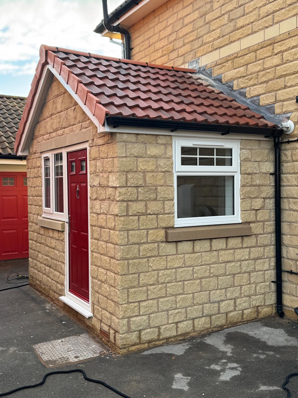 Stone-effect brick porch extension with red tiled pitched roof