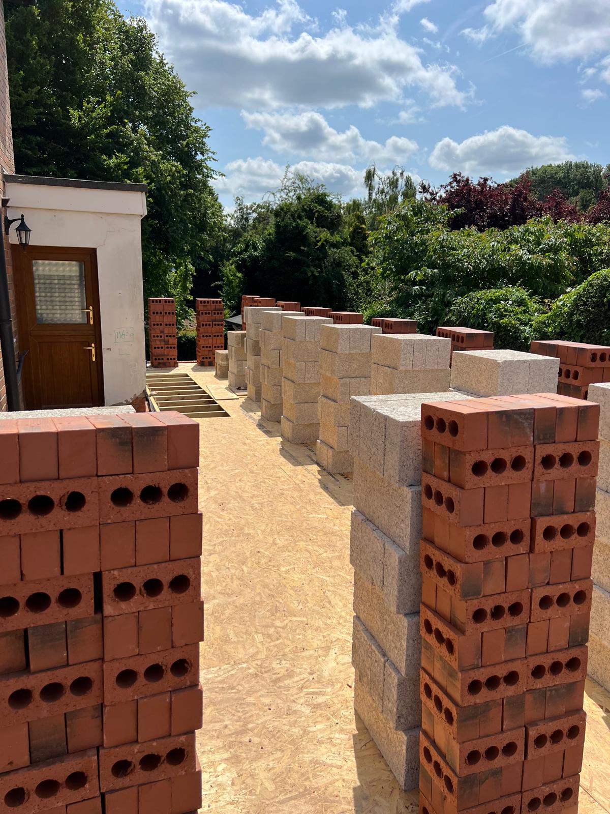 Premium building materials staged on site — red facing bricks and concrete blocks